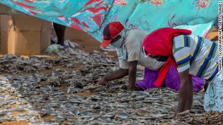 Workers process salted fish in Negombo, where plastic raw materials and other debris washed ashore.