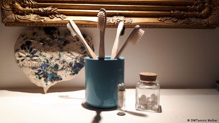 Pot containing bamboo toothbrushes, a jar of tooth tabs and dental floss