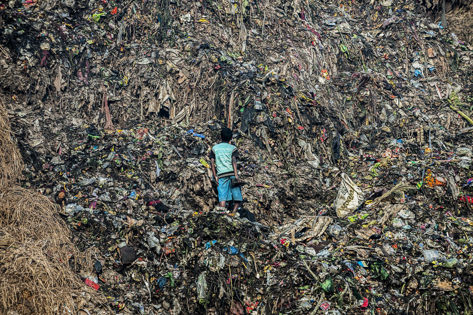 A child facing a mountain of garbage.