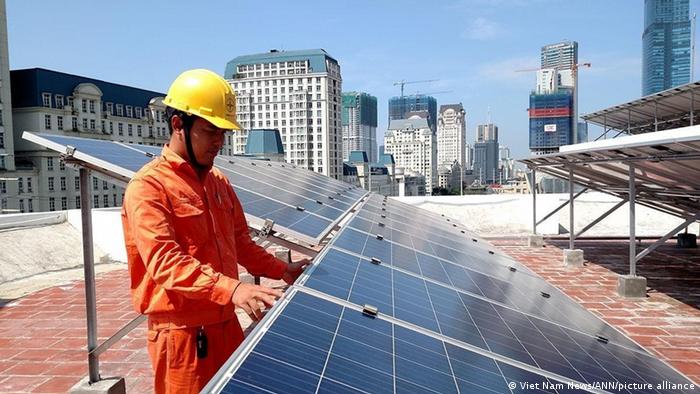 A worker installing a solar panel in Vietnam