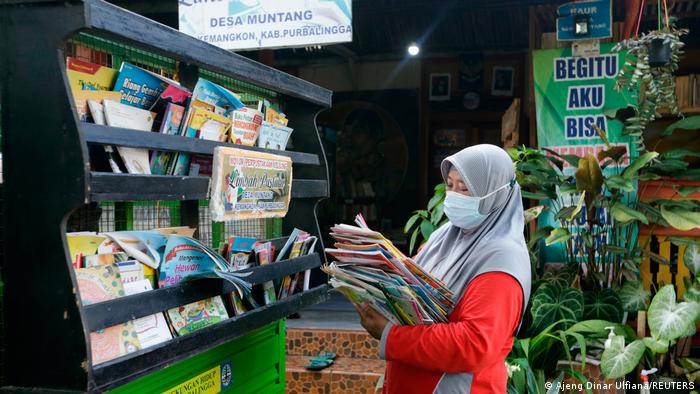 Raden Roro Hendarti arranging her collection of books on her three-wheeler vehicle.