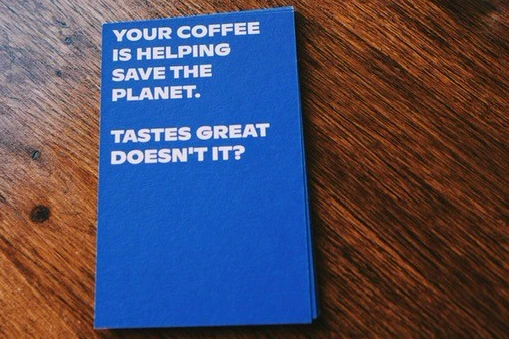 A blue flyer reads your coffee is helping save the planet, tastes great doesn't it? 
