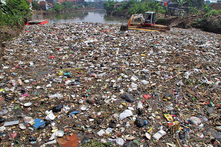 A backhoe grapples with garbage in the Cikapundung River