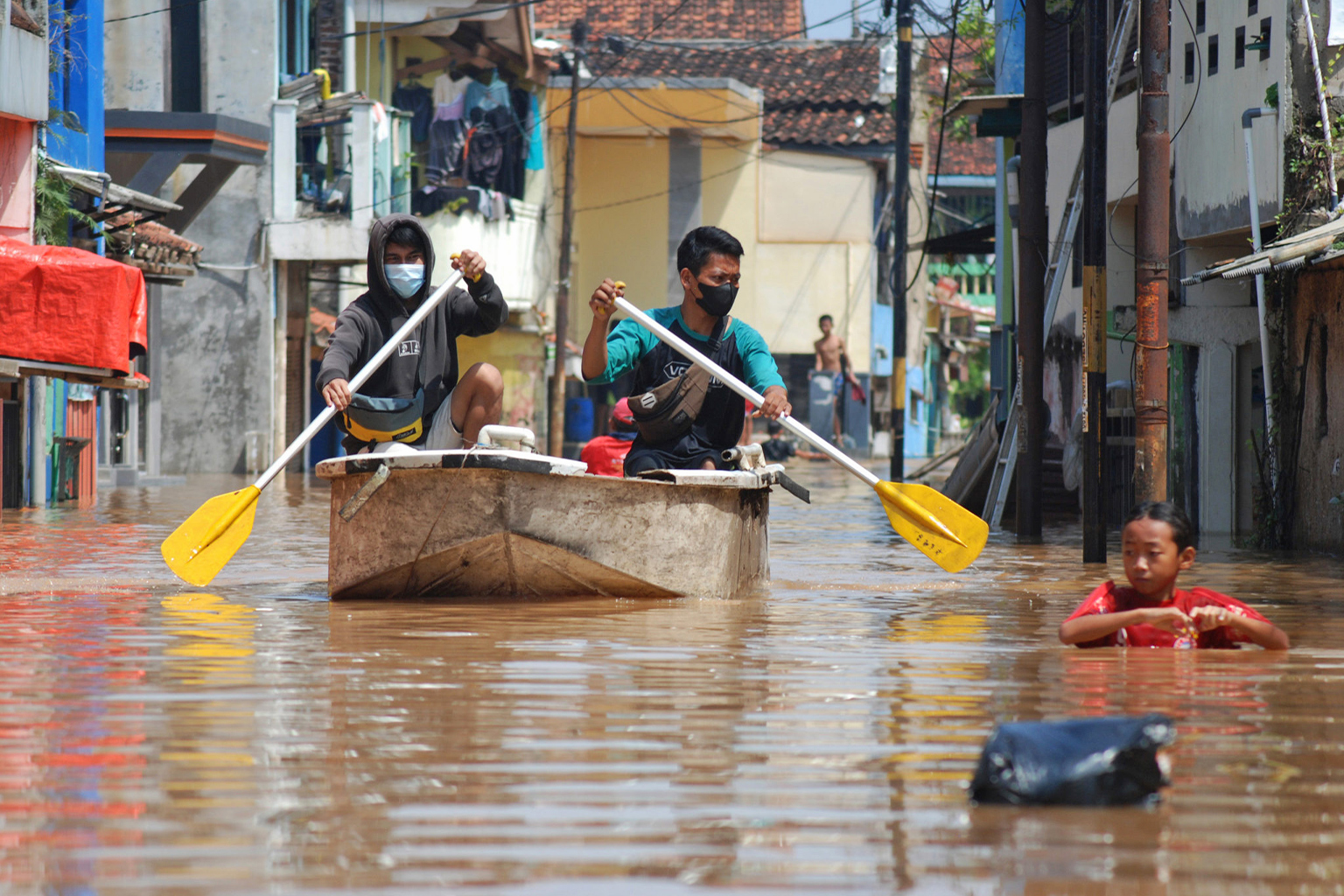 Residents paddle a boat down a flooded street