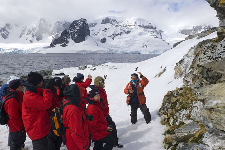 Group of tourists in Antarctica listening to a lecture from a scentist