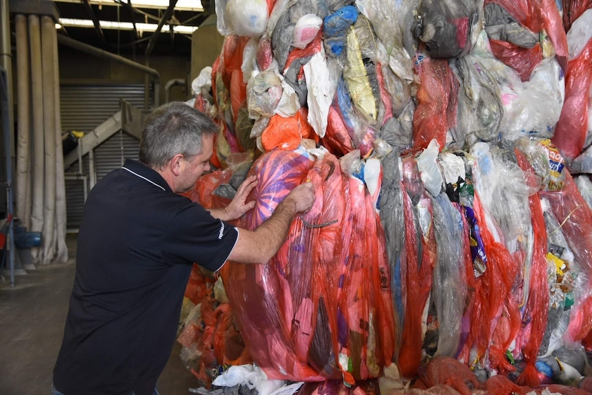 A man Yates inspects a bail of the plastic bags of recycling 