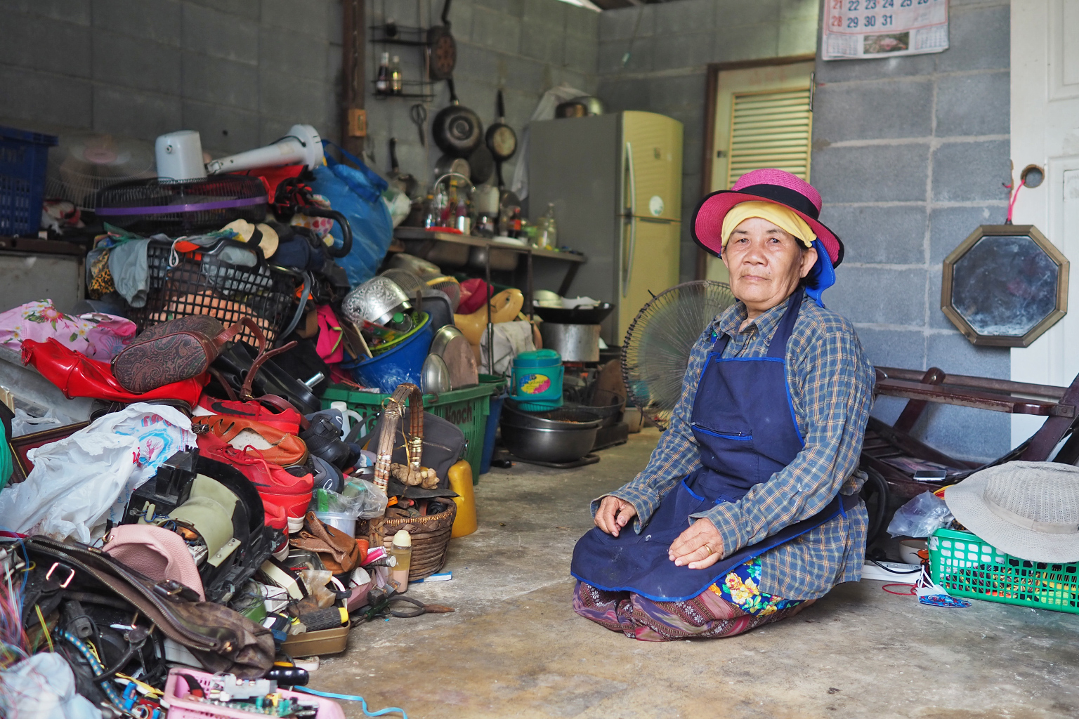 A resident of Thalang sits next to a collection of household waste.