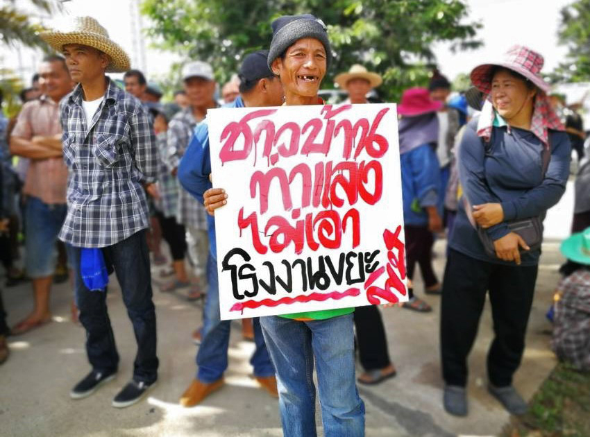 Thalang residents hold signs protesting.