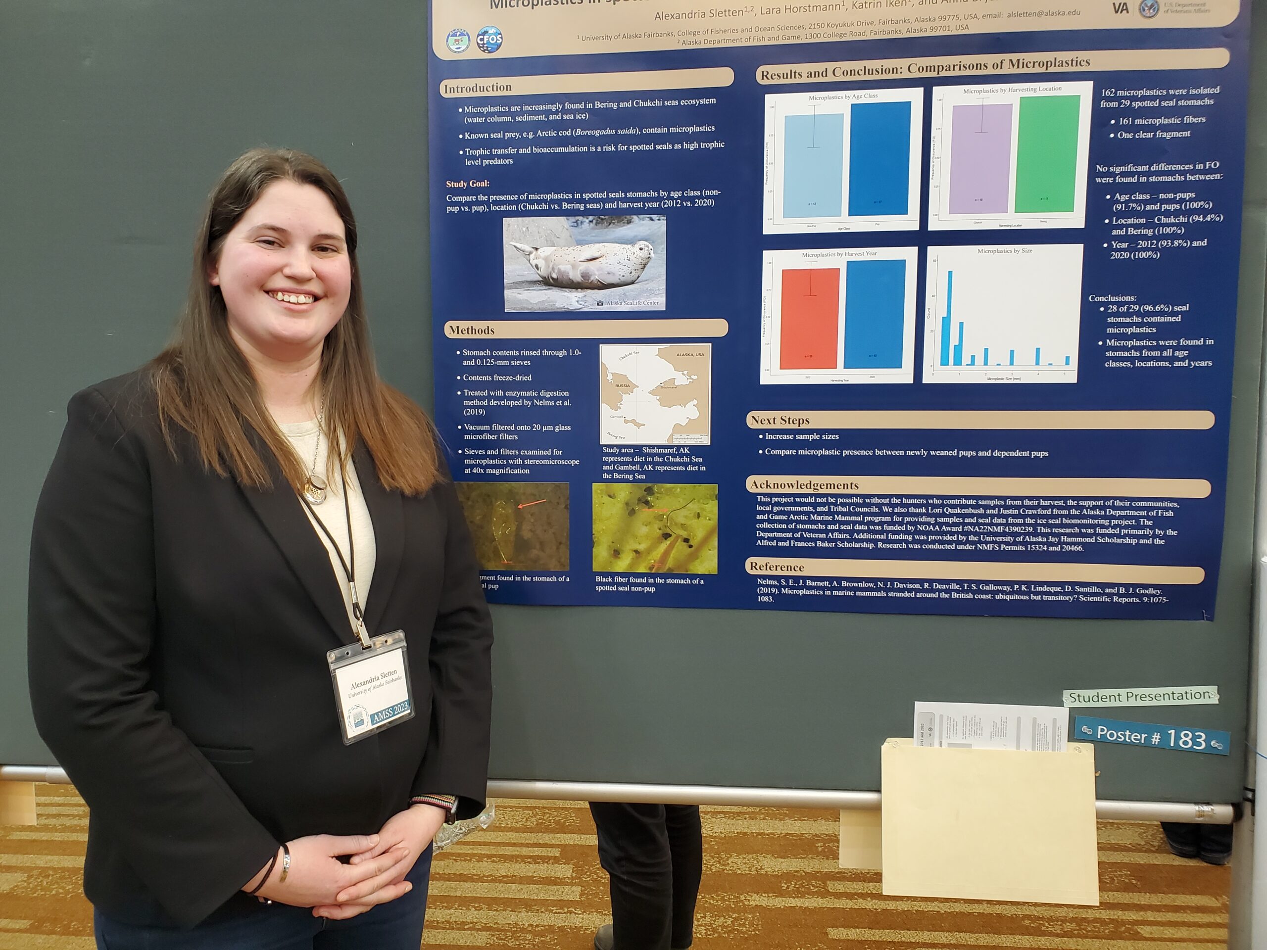 UAF graduate student Alexandria Sletten stands on Tuesday by her poster describing her research into microplastics ingested by spotted seals. She discussed her work during a poster session at the Alaska Marine Science Symposium. (Photo by Yereth Rosen/Alaska Beacon)