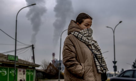 A girl wears a scarf over her face as she walks past a factory in the North Macedonian capital